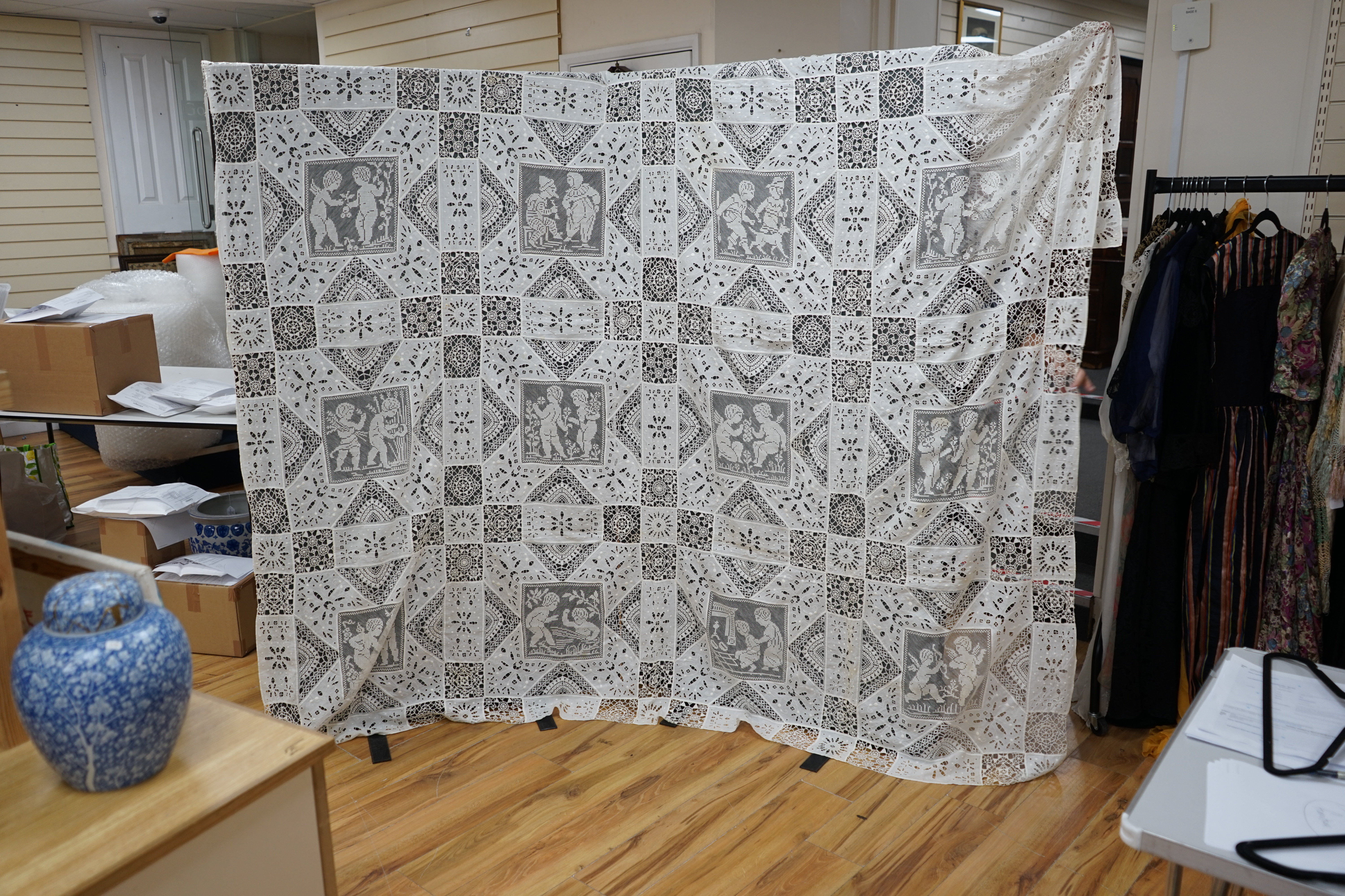 An early 20th century Italian ornate bedcover, worked with square fillet lace insertions of putti, white multi patterned cut work squares on fine linen and similar multi patterned needle lace squares, creating a unique b